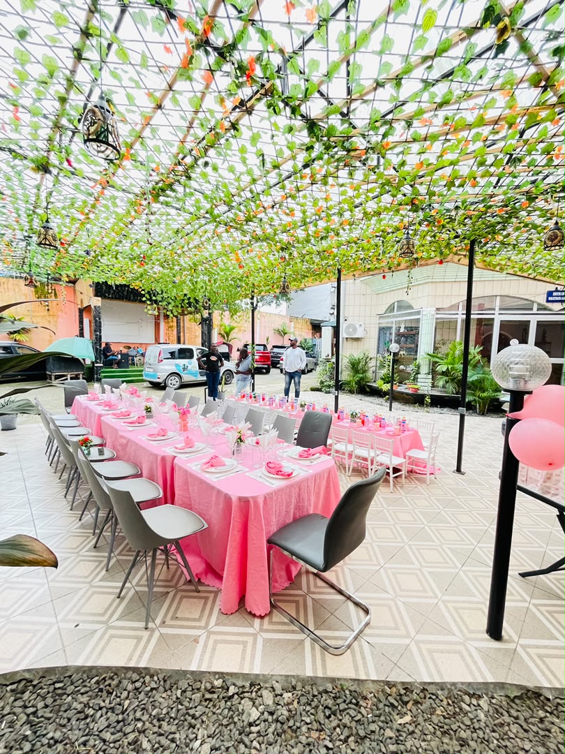 Cour du restaurant Le Méditerranée dressée pour un banquet, longues tables nappées sous une tonnelle de feuillage